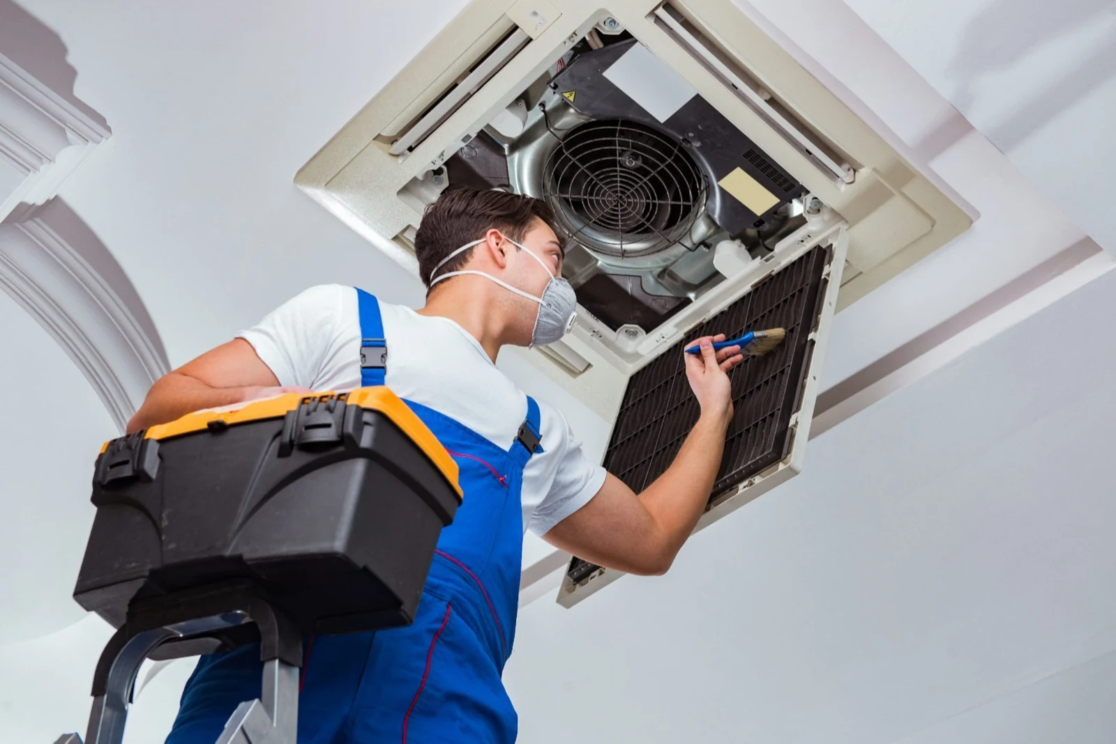 Technician servicing an open ceiling-mounted cassette air conditioning system