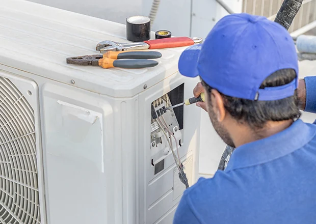 Technician servicing an outdoor air conditioner electrical panel