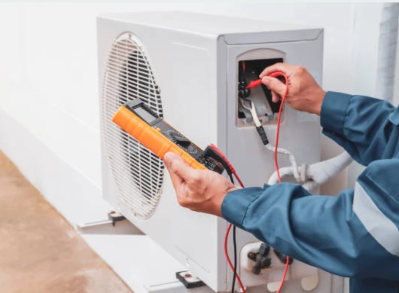 Technician measuring electrical voltage at an outdoor air conditioning unit