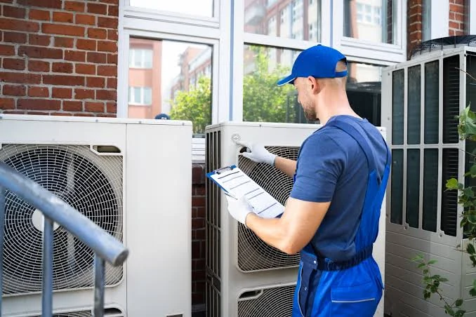 Technician inspecting outdoor air conditioning units with a clipboard