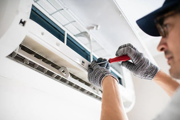Technician using a screwdriver to service a wall-mounted air conditioner
